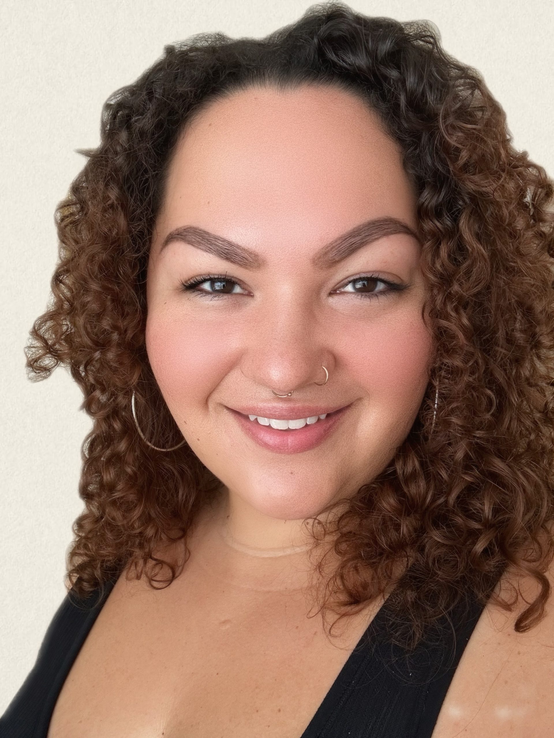 Professional headshot of Natasha. She is a female presenting person with curly hair.
